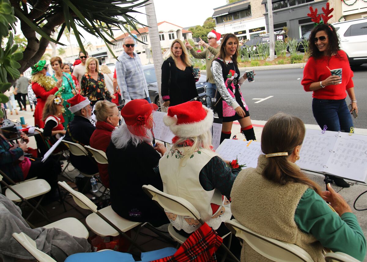 People walk along and listen to Christmas carols from the Oasis Ukulele group.