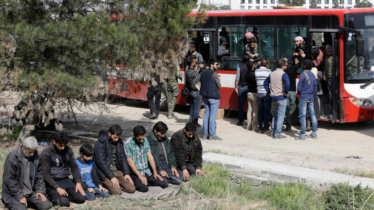 People evacuated from eastern Ghouta conduct noon prayers on the side of the road after arriving at a government-held area at the entrance of Harasta on the outskirts of the capital Damascus.