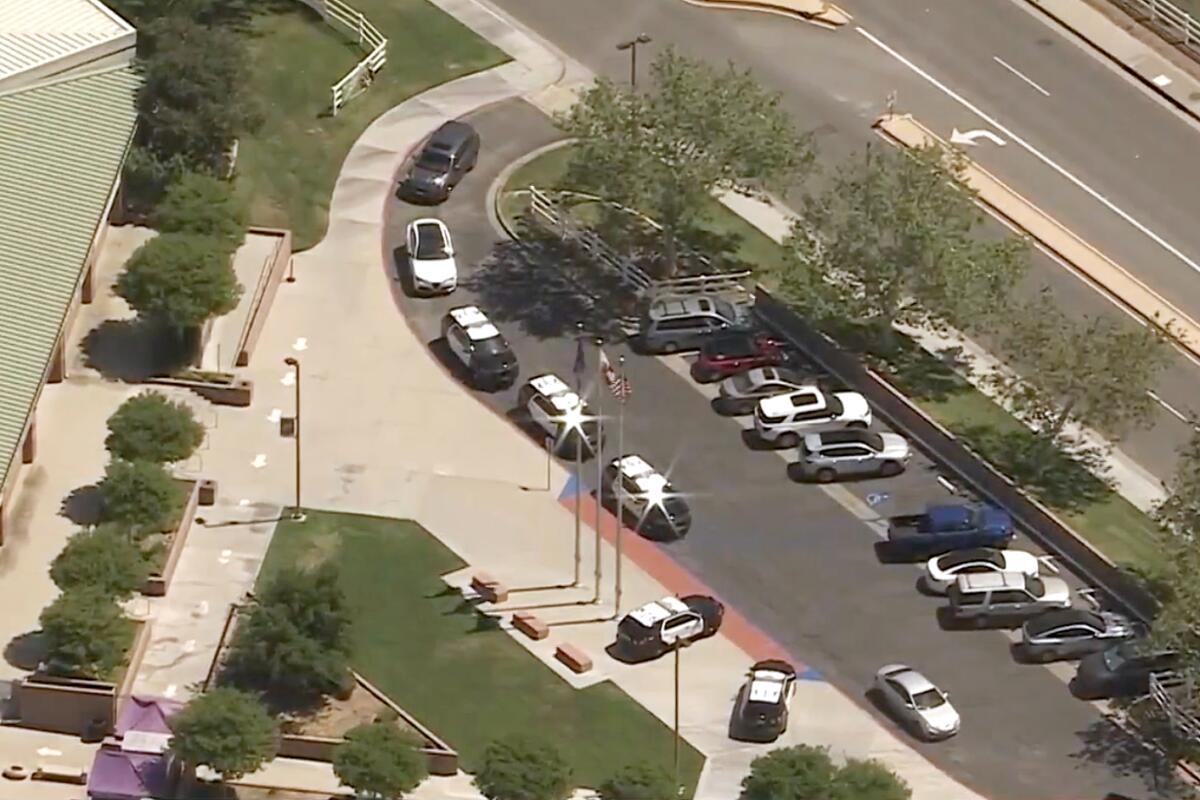 Aerial view of an exterior of Valencia High School, with police cruisers parked in front.