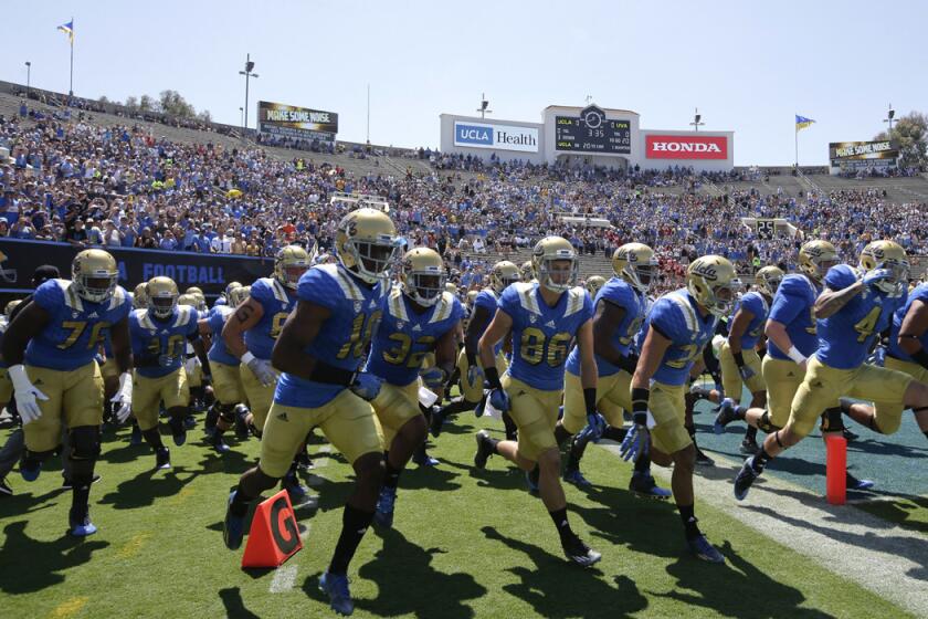 UCLA players run onto the field before a game against Virginia at the Rose Bowl on Sept. 5.