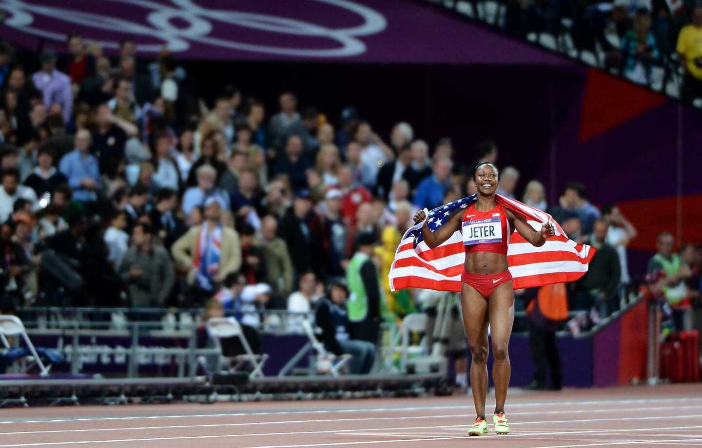 Carmelita Jeter carries the American flag after winning the silver medal in the 100 meters at the 2012 London Olympics.