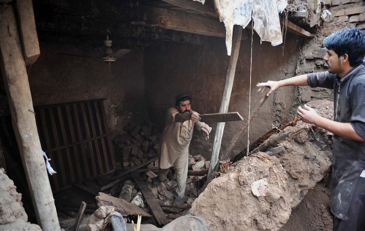 People remove debris from a damaged house after heavy rains devastated the outskirts of Peshawar on April 3, 2016. (A Majeed / AFP/Getty Images)