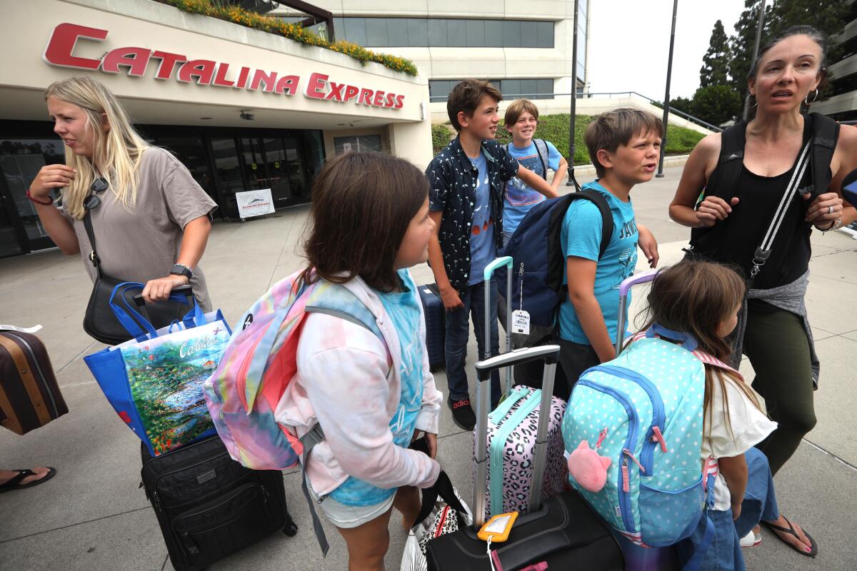 A group of people with backpacks and suitcases stand outside