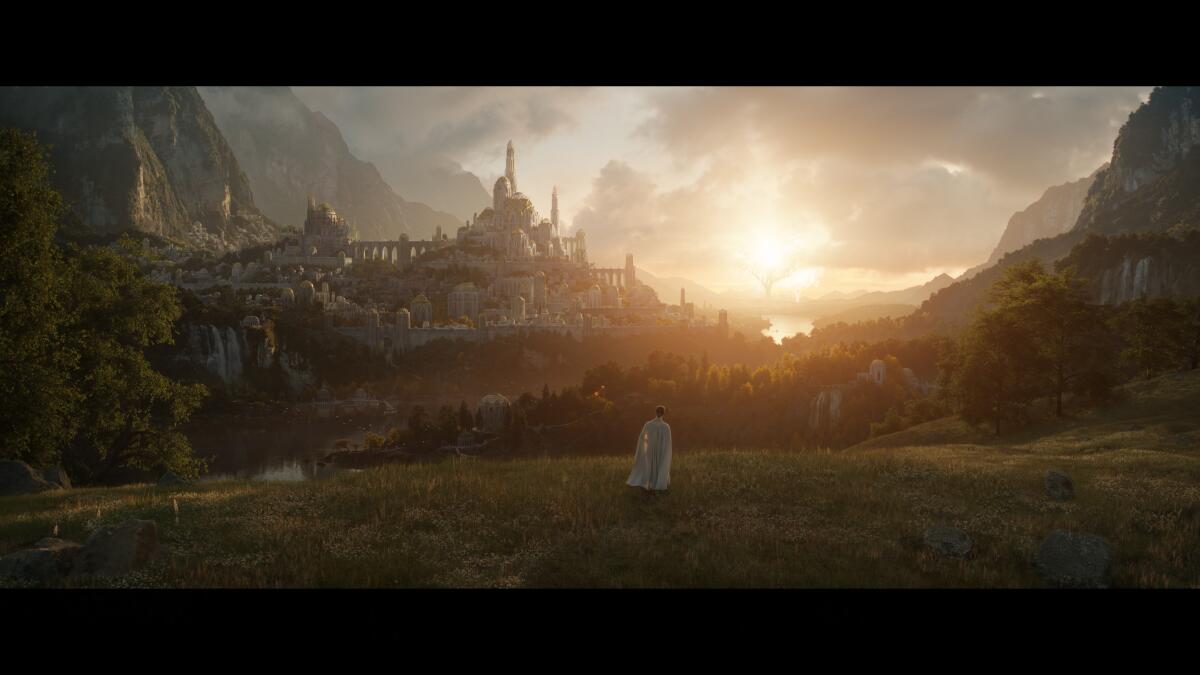 A lone figure in white looks down over a gleaming hilltop city at dusk.