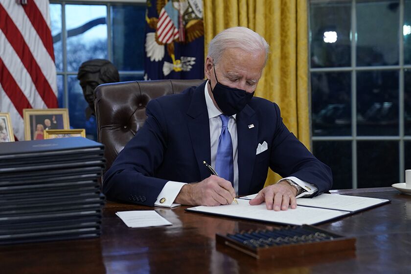President Joe Biden signs his first executive orders in the Oval Office.