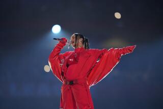 Rihanna sings into a microphone while wearing a red belt, puffy red jacket and red bodysuit accentuating her baby bump.