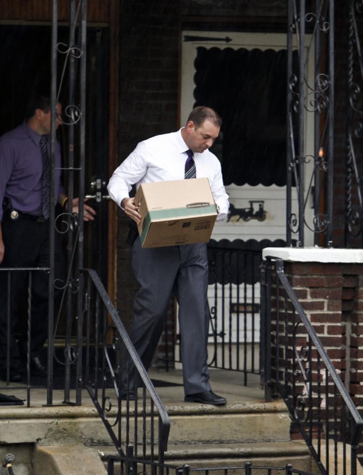 Investigators carry evidence from the home of Griffin Campbell in Philadelphia. Campbell's construction company was handling the demolition of a building last week when it collapsed into a neighboring store, killing six.