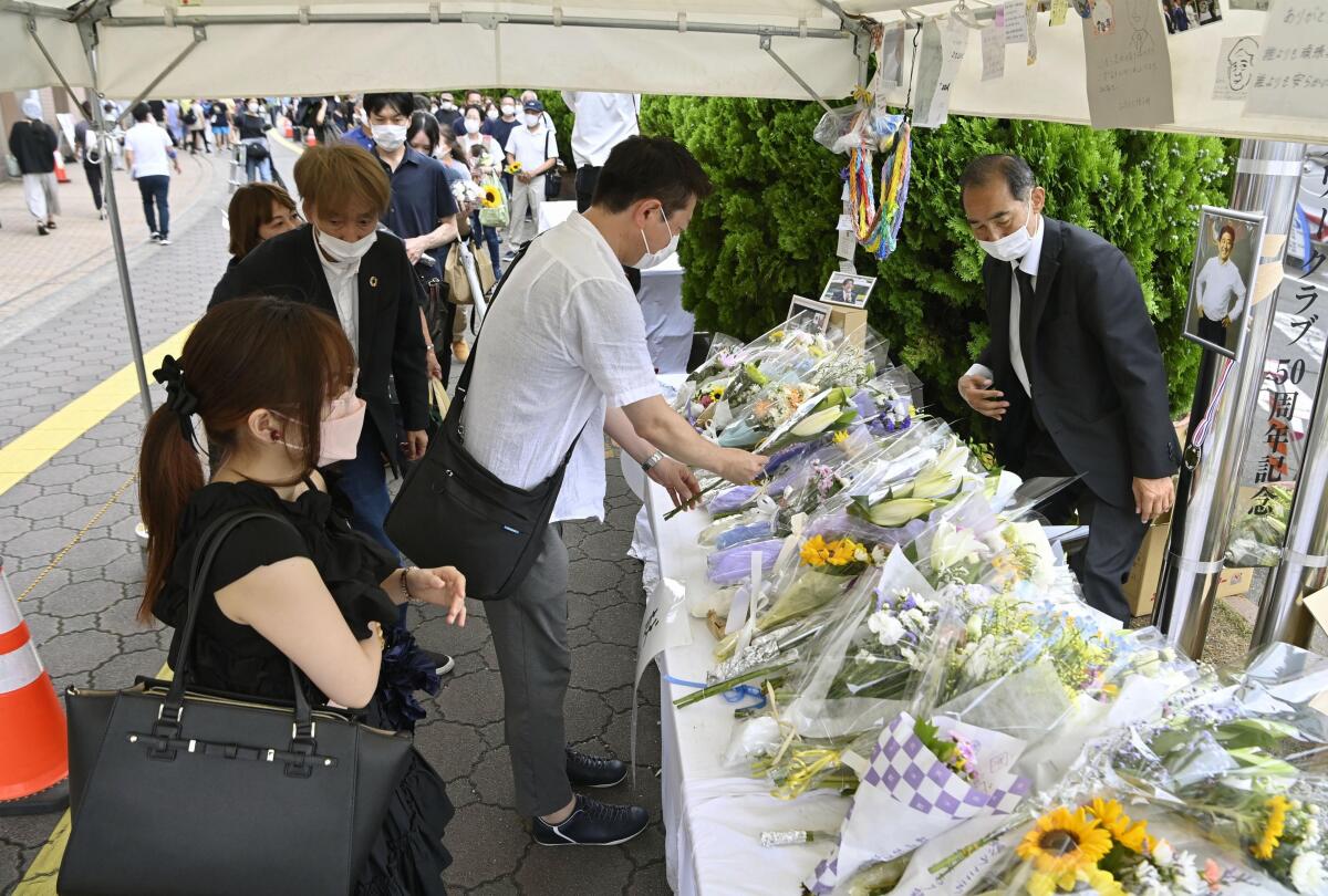 People offer flowers at a memorial area near the site where former Japanese Prime Minister Shinzo Abe was fatally shot in Nara, western Japan, Friday, July 15, 2022. Many people mourned the death of Abe at the site where he was gunned down during a campaign speech a week ago Friday, shocking a nation known for its low crime rate and strict gun control. (Kyodo News via AP)
