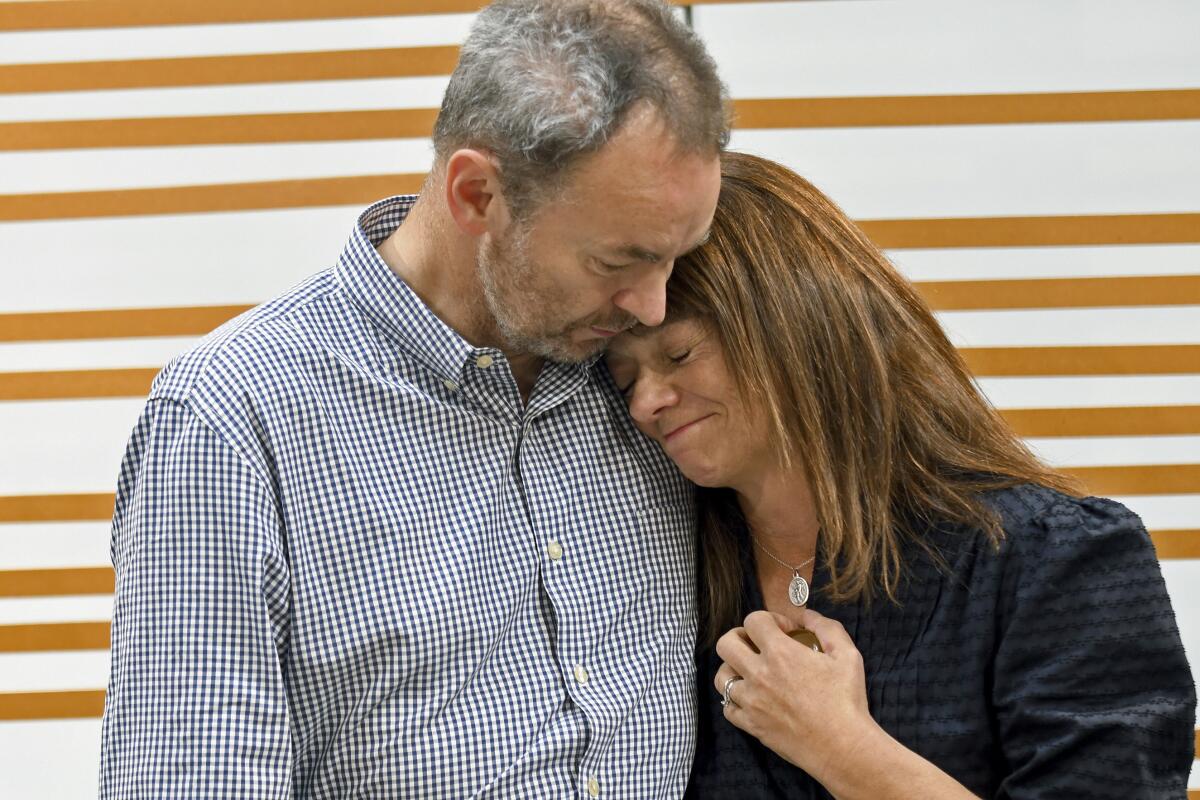 Husband and wife comforting each other during an emotional news conference