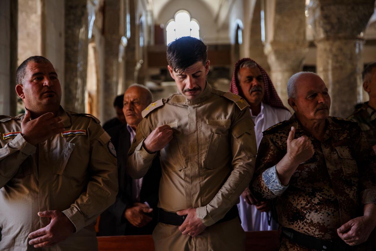 Soldiers make the sign of the cross during Easter Mass at the Mar Youhanna Church, also known as St. John Church, in Iraq. (Marcus Yam / Los Angeles Times)