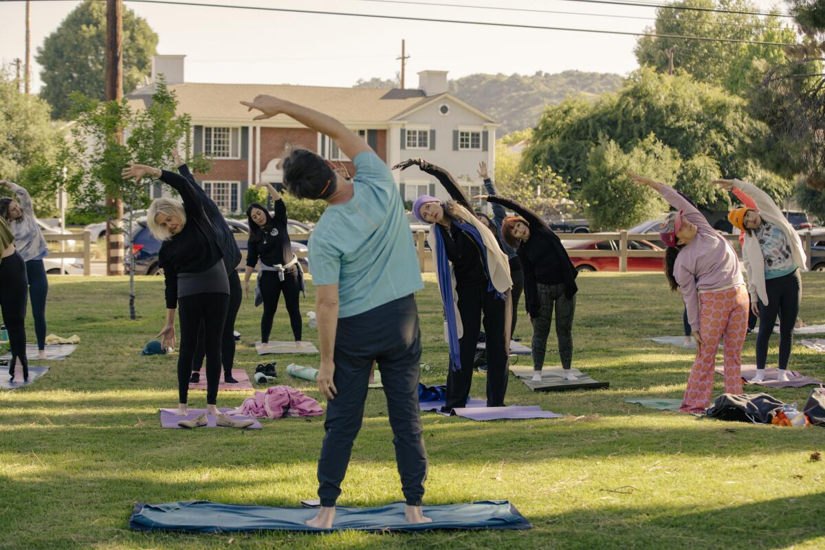 A group of people doing yoga in a park.