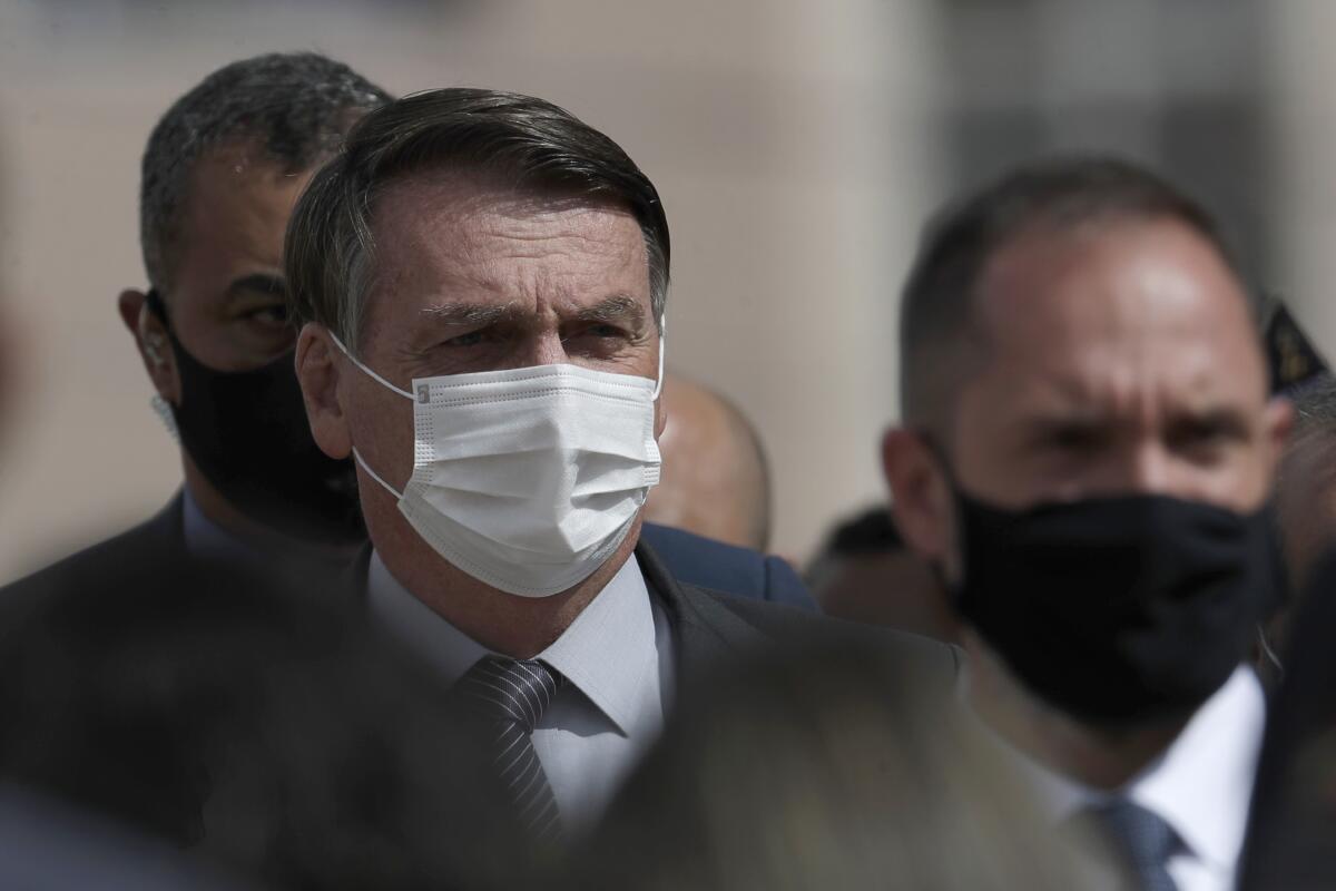 Wearing a mask to curb the spread of the new coronavirus, Brazil's President Jair Bolsonaro arrives for a ceremony to deliver affordable homes built by the government, in a neighborhood of Brasilia, Brazil, Monday, Apr. 5, 2021. (AP Photo/Eraldo Peres)