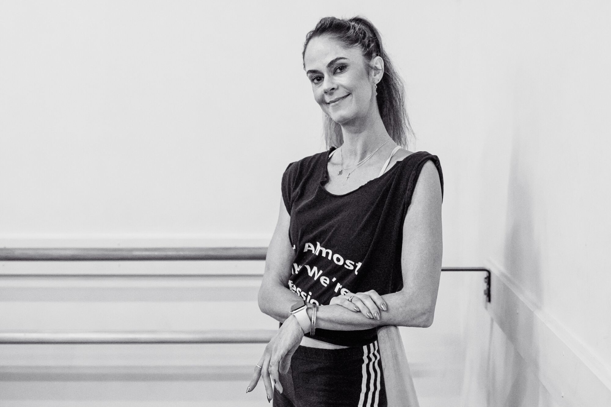 A woman leans on a ballet rail.