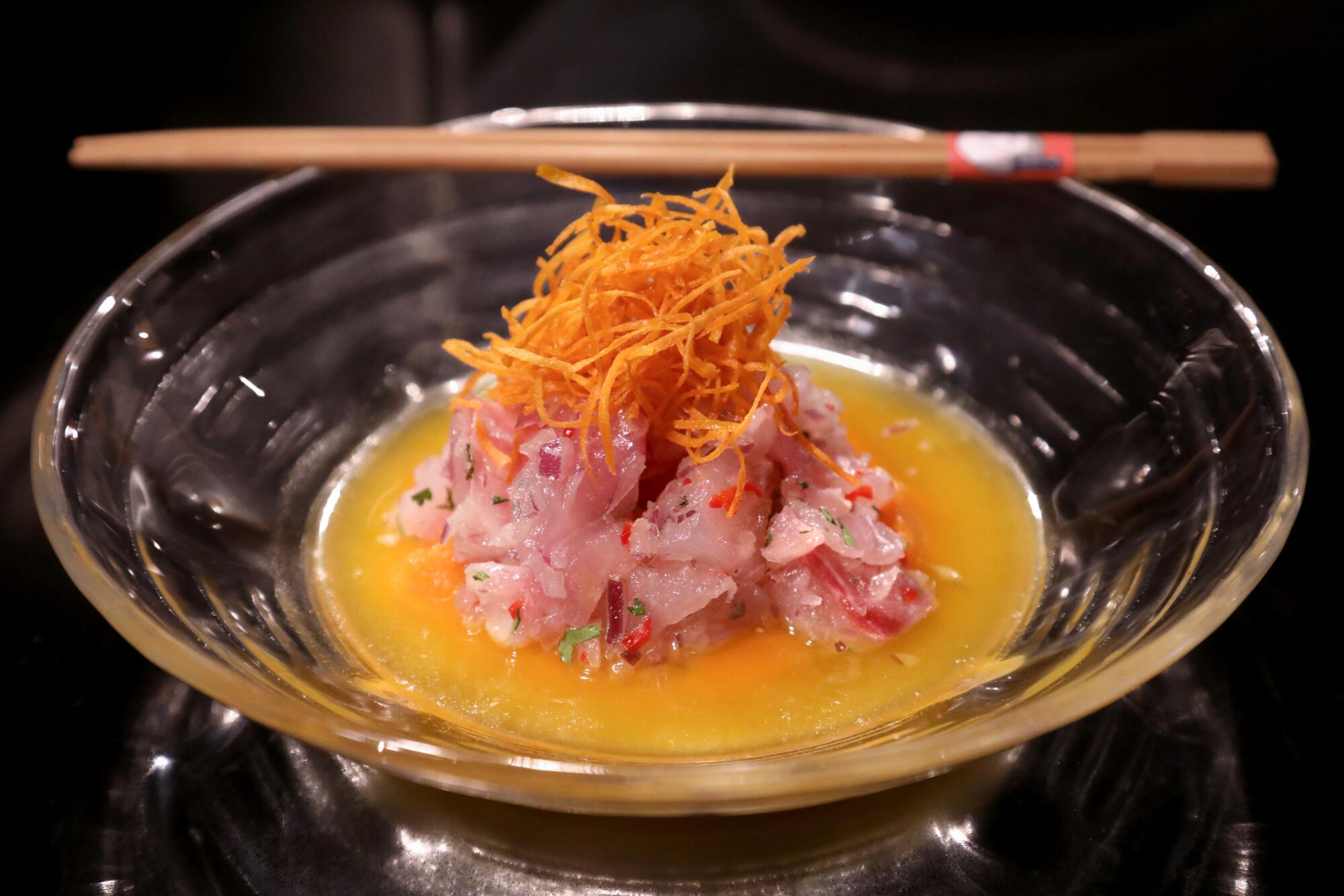 Peruvian ceviche, stacked, rested in orange sauce in a glass bowl