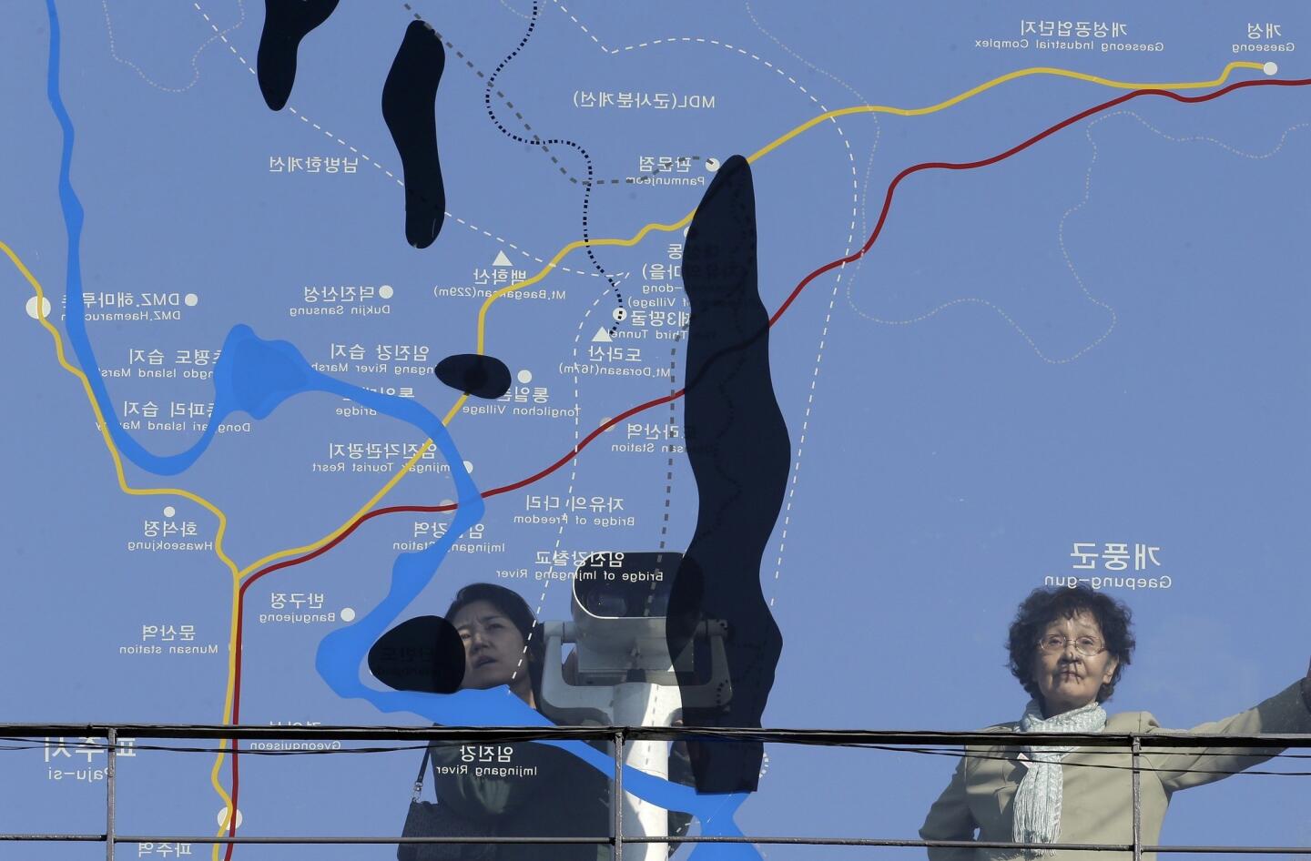 Visitors look toward North Korea through a map of the area around the demilitarized zone near the border village of Panmunjom.