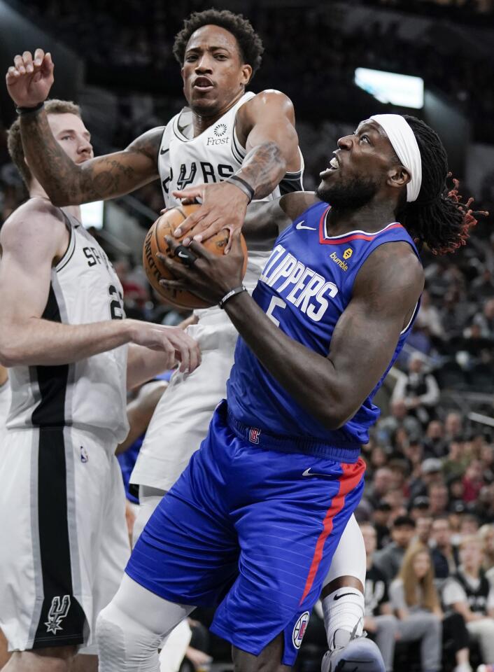 Clippers forward Montrezl Harrell tries to put up a shot against Spurs guard DeMar DeRozan during the first half of a game Nov. 29.
