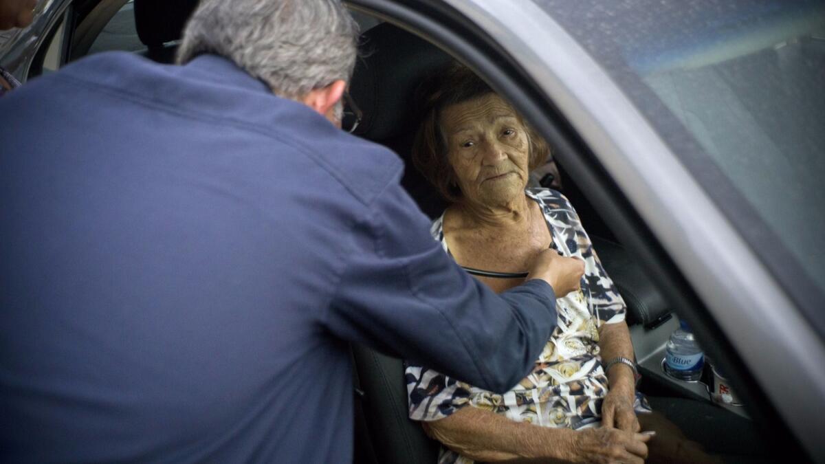 Carmen Hernández es examinada por un médico en un auto en las afueras del hospital al que fue llevada luego de sufrir una caída el 28 de septiembre del 2017 en Bayamón.