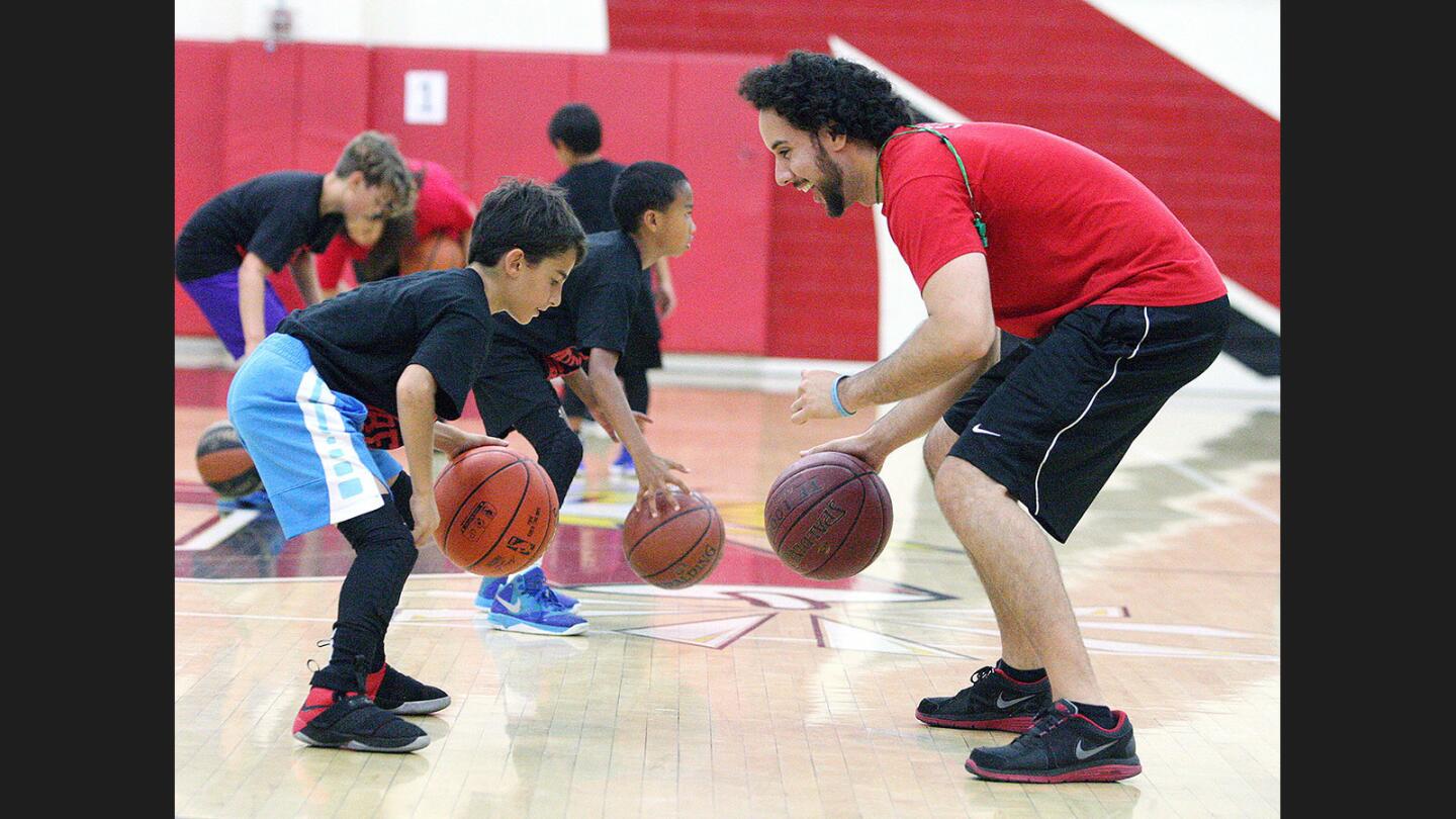 Alexander Aghaian, 11, of Glendale, dribbles the baseketball with camp director Ib Belou at Coach Belouâ€™s 2017 Summer Basketball Camp at Glendale High School on Monday, July 17, 2017.