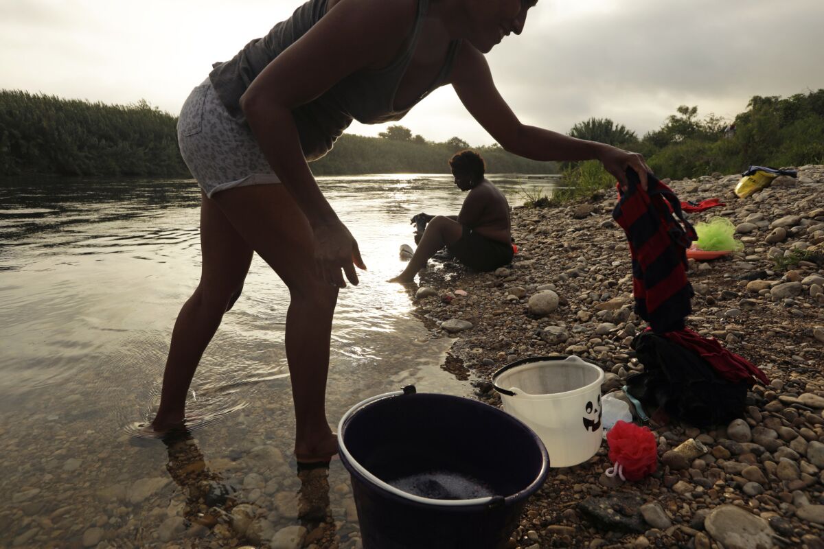 Two women bathe and wash their clothes while camping with other African and Cuban asylum seekers. (Carolyn Cole/Los Angeles Times)
