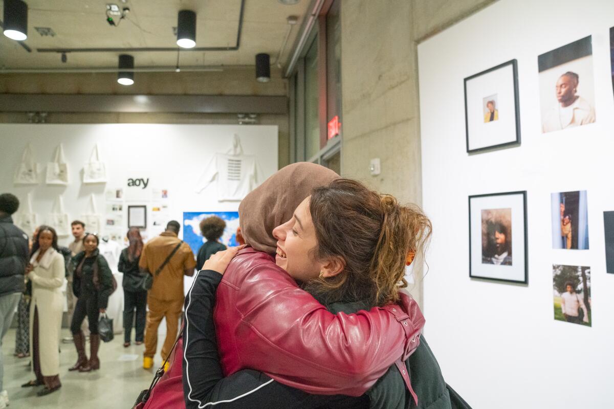 Friends embrace at an art exhibit at a recent Abundance of Youth event at UC San Diego.