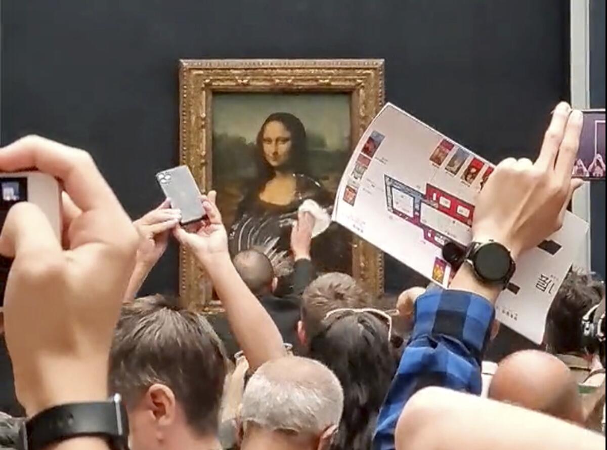 A security guard cleans the Mona Lisa, surrounded by tourists taking pictures
