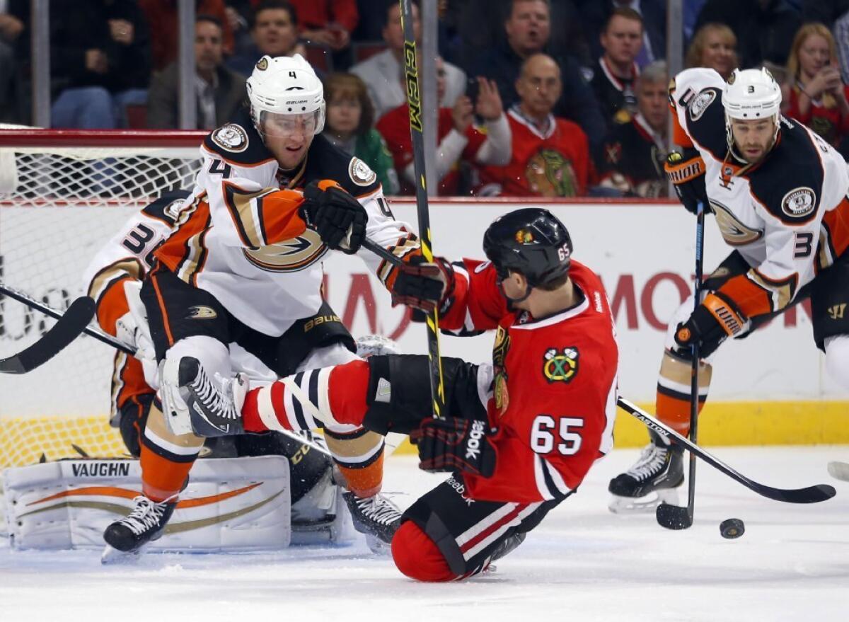 Ducks defenseman Cam Fowler (4) pushes down Blackhawks center Andrew Shaw (65) during the first period of an NHL hockey game Tuesday, Oct. 28, 2014, in Chicago.