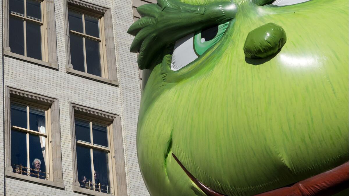The Grinch balloon passes by windows of a building on Central Park West during Macy's Thanksgiving Day Parade in New York on Nov. 23, 2017.