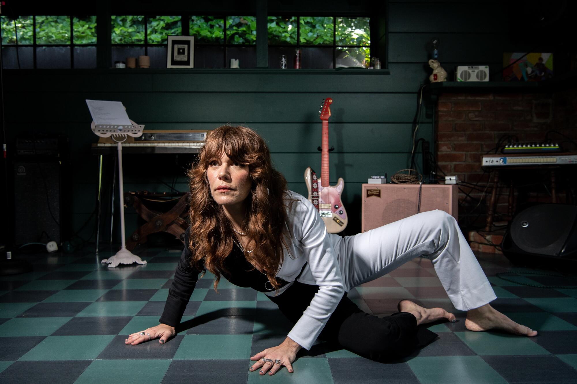 In what looks like a black and white jumpsuit, a barefoot Jenny Lewis strikes a pose on the floor of  her L.A. home.  