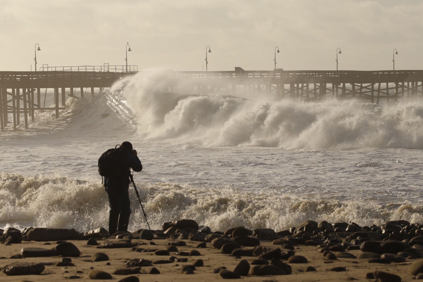 Photographer Dan Dolinh takes photos as the Ventura Pier is pounded by heavy surf Thursday morning.