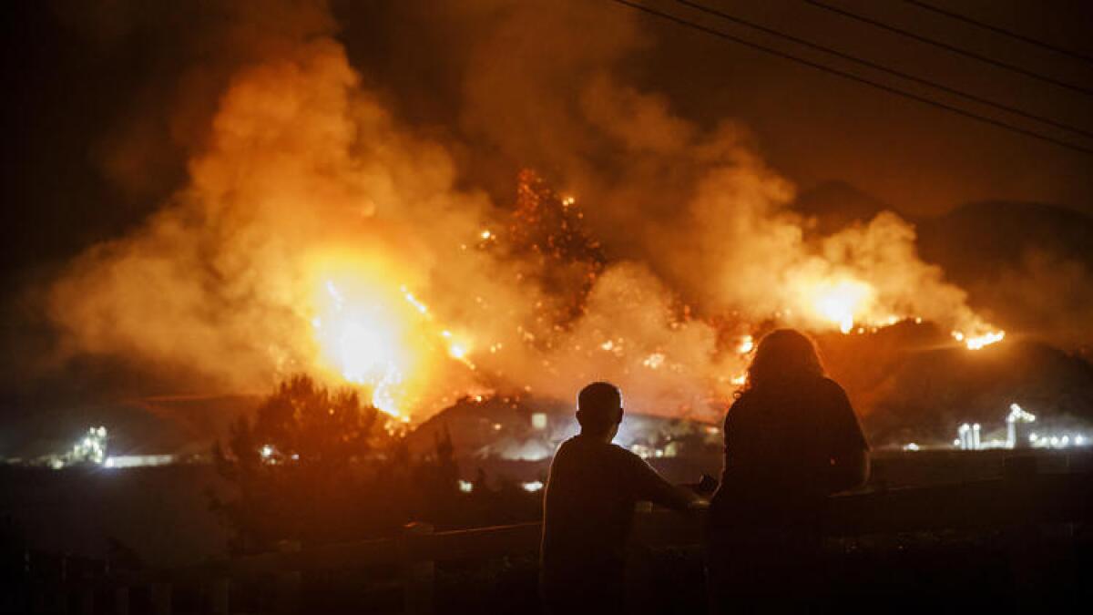 People watch as the Holy fire rages on a mountainside in Temescal Valley.