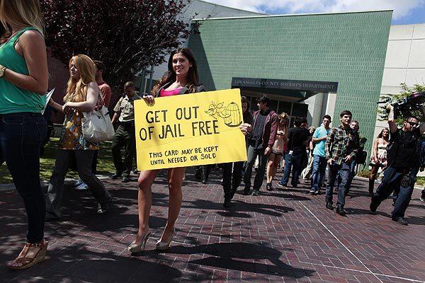 An extra carries a prop sign for a scene where character Vincent Chase is arriving at court.