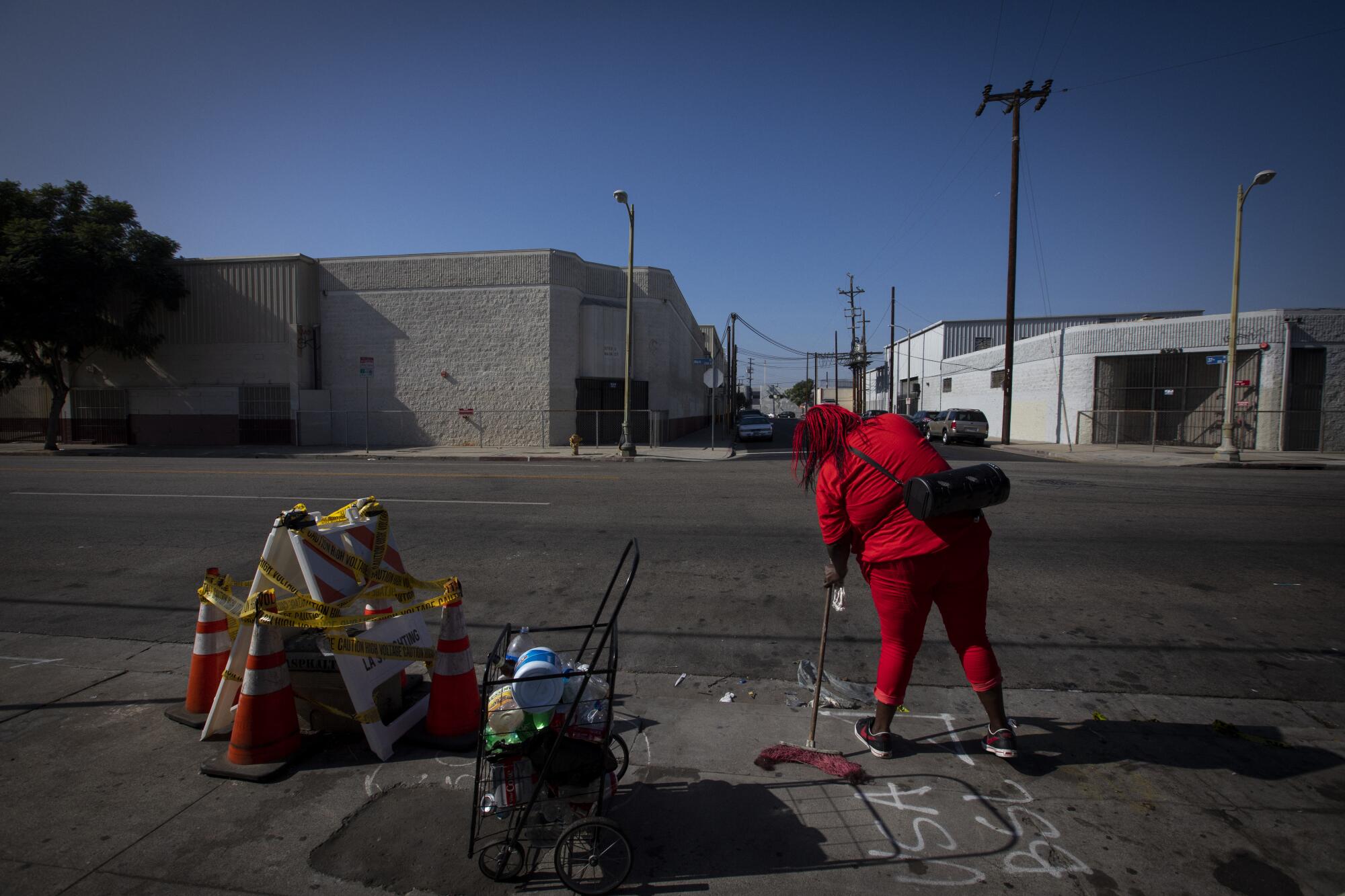 Leneace Pope cleans the sidewalk outside her tent. 