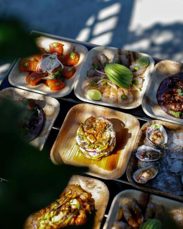 Square takeout containers filled with a variety of seafood dishes