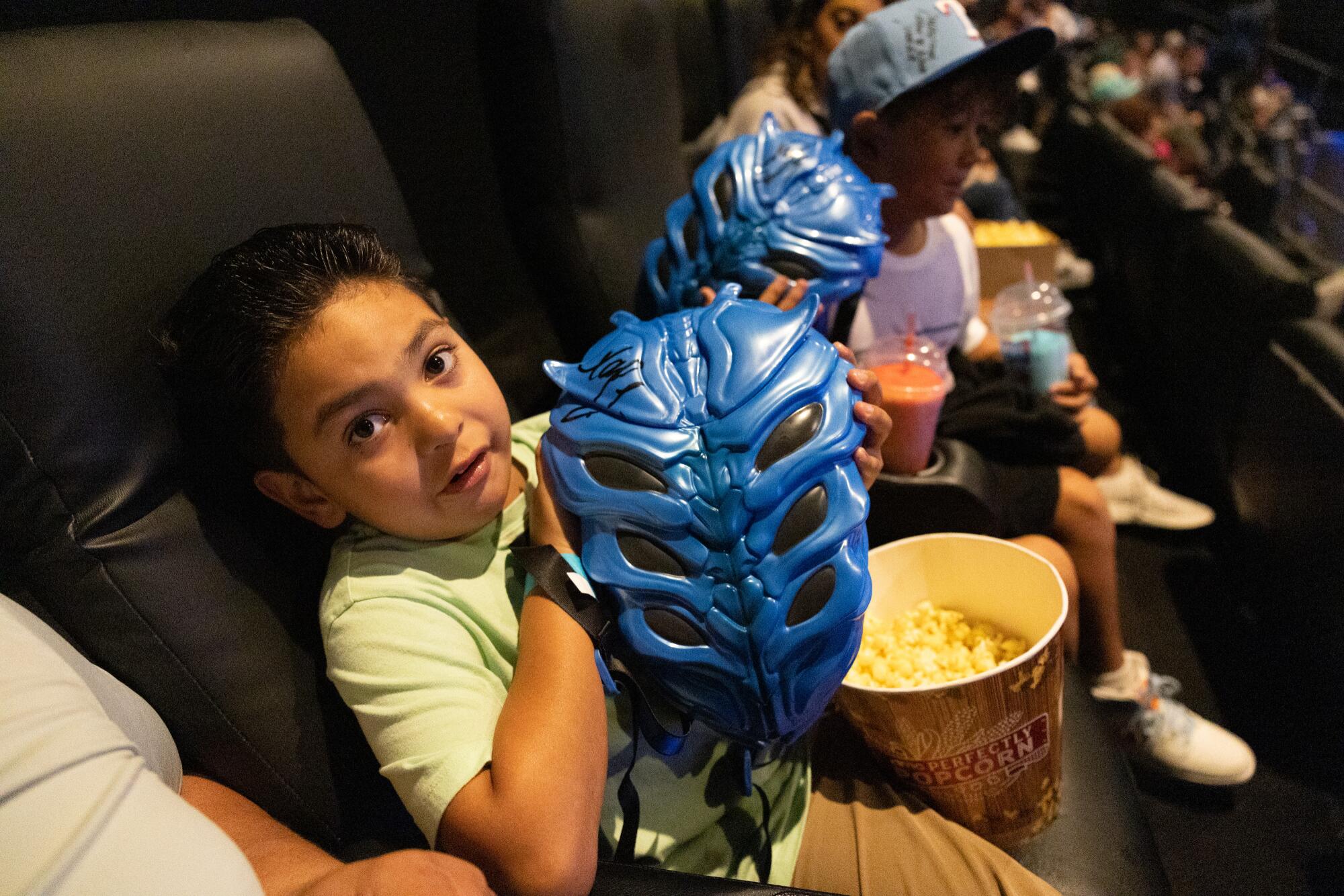 A child holds a "Blue Beetle" backpack.