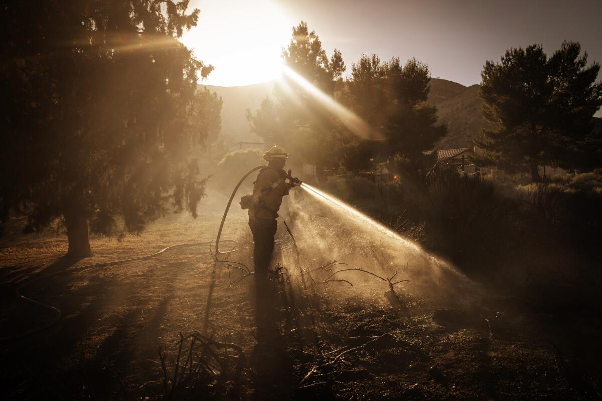 A firefighter sprays water from a hose onto the ground.