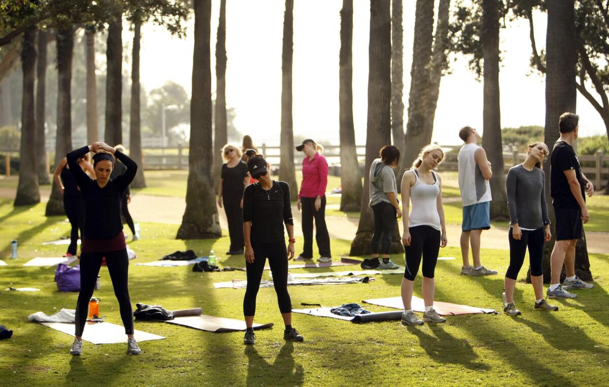 Students stretch at the conclusion of a fitness class workout at Palisades Park in Santa Monica in January. The City Council has recently set restrictions on and established fees for the use of public parks for training.