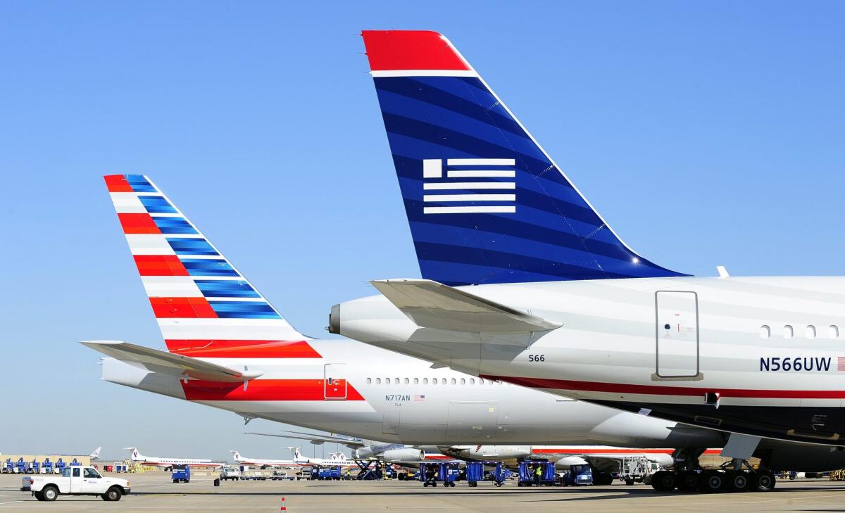 American Airlines and US Airways jets wait at the Dallas/Fort Worth International Airport in 2013. The merger of the two carriers takes a key step Oct. 17 when the reservations for US Airways flights are absorbed into American Airlines' system.