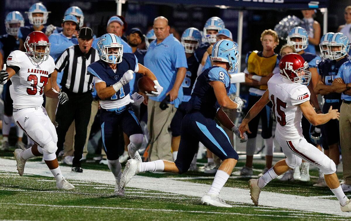 Bradley Schlom of Corona del Mar cuts inside as teammate Carter Duss (9) delivers a block, allowing Schlom to return a punt 69 yards for a touchdown against Lakewood on Friday at Newport Harbor High.