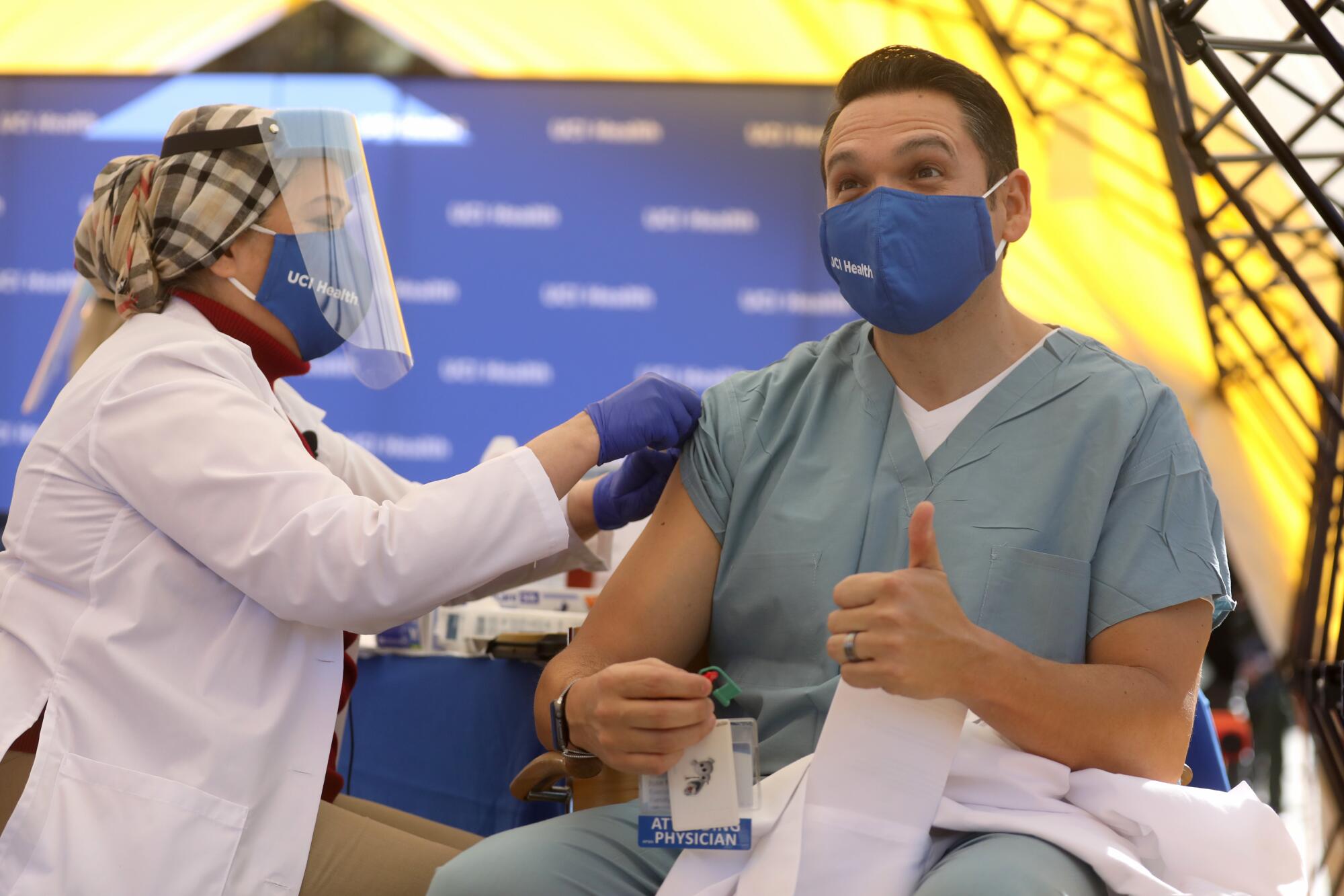 Jose Mayorga, right, medical doctor UCI Health, gives a thumbs up after receiving a Pfizer BioNTech COVID-19 vaccine.