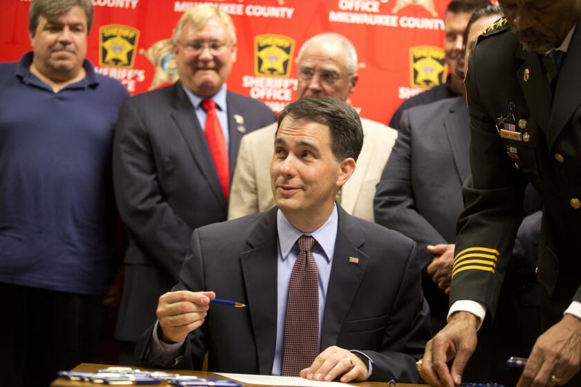 Wisconsin Gov. Scott Walker signs a bill Wednesday in Milwaukee that eliminates a 48-hour waiting period for handgun purchases.