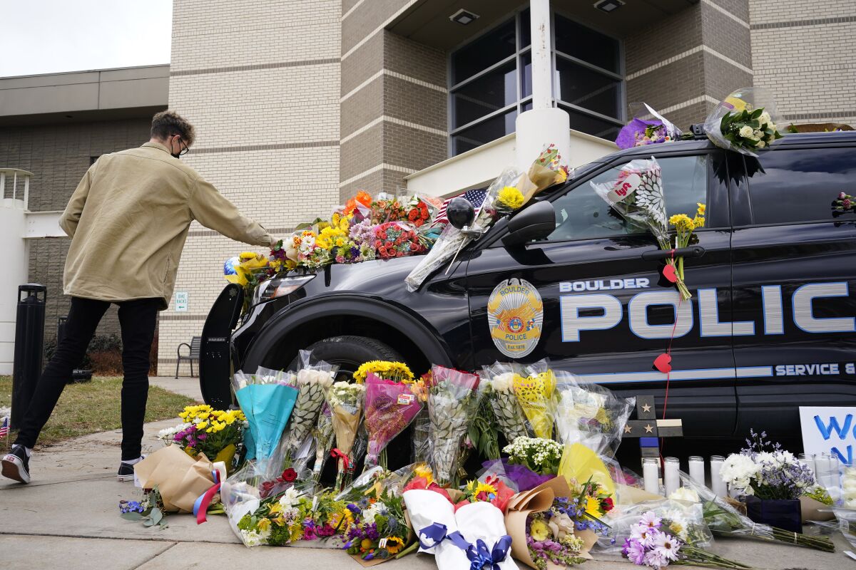 A man leaves a bouquet on a police cruiser