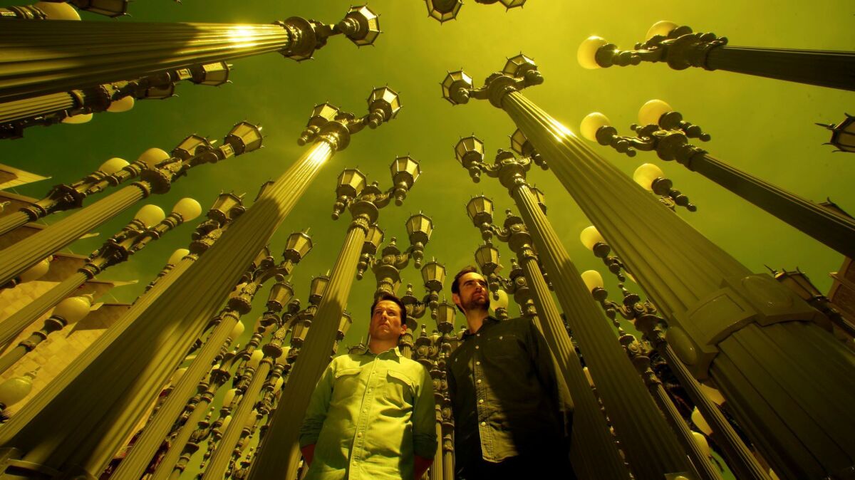Richard Dewey, left, and Timothy Marrinan, the directors of a new documentary about the late Los Angeles artist Chris Burden, stand amid his sculpture "Urban Light" at LACMA.
