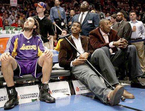 Lakers center Andrew Bynum stretches out on the bench between teammates Sasha Vujacic, left, and DJ Mbenga with his injured right knee Monday night during the game against the New York Knicks at Madison Square Garden.