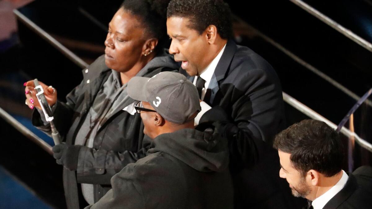 Denzel Washington, center, mock-marries an engaged couple with Jimmy Kimmel looking on during the 89th Academy Awards.