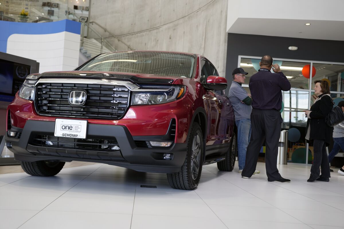 FILE - Customers confer with a salesperson as a 2022 Ridgeline pickup truck sits on the showroom floor of a Honda dealership, Friday, April 15, 2022, in Highlands Ranch, Colo. (AP Photo/David Zalubowski, File)