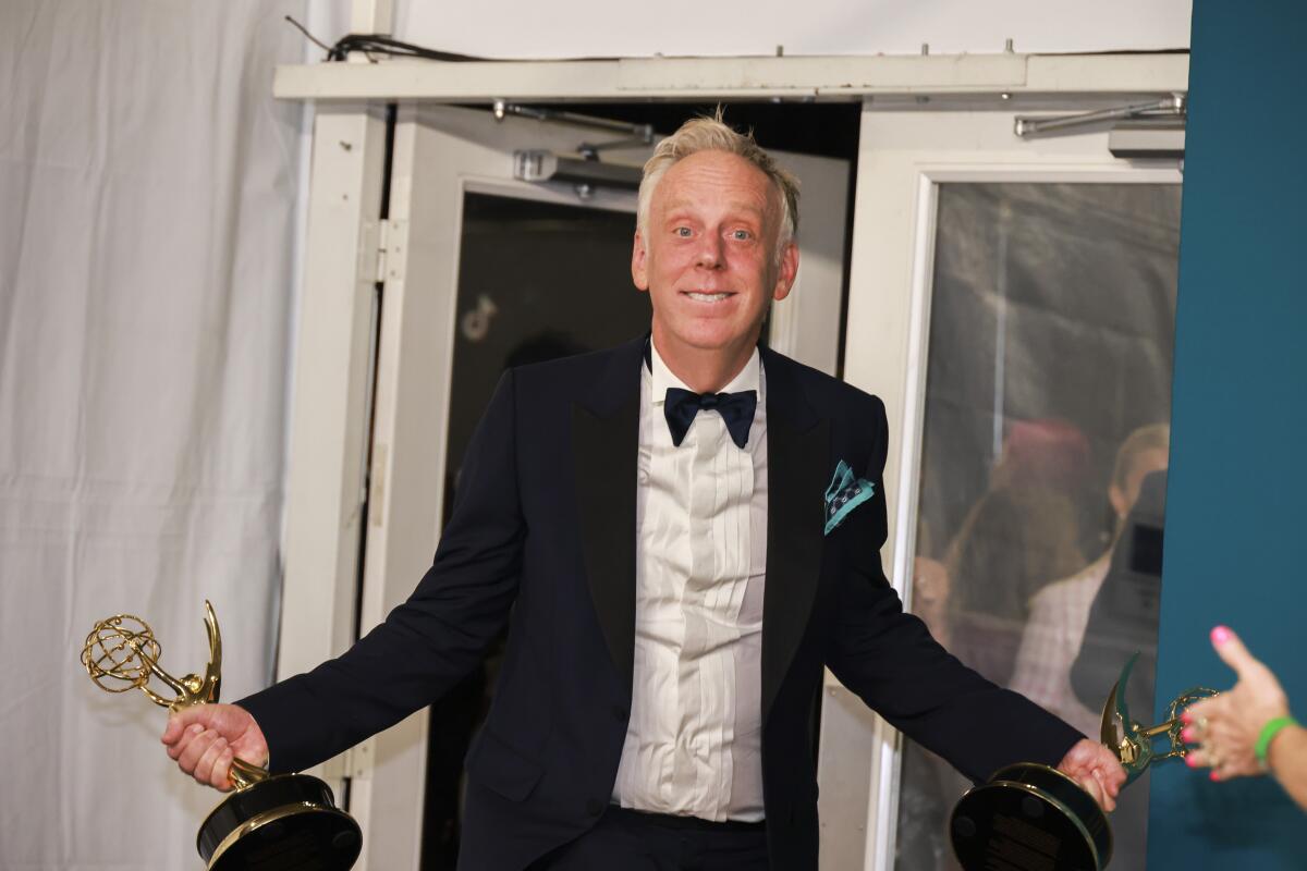 Mike White dressed in a tuxedo holds two Emmys at the 2022 celebration.