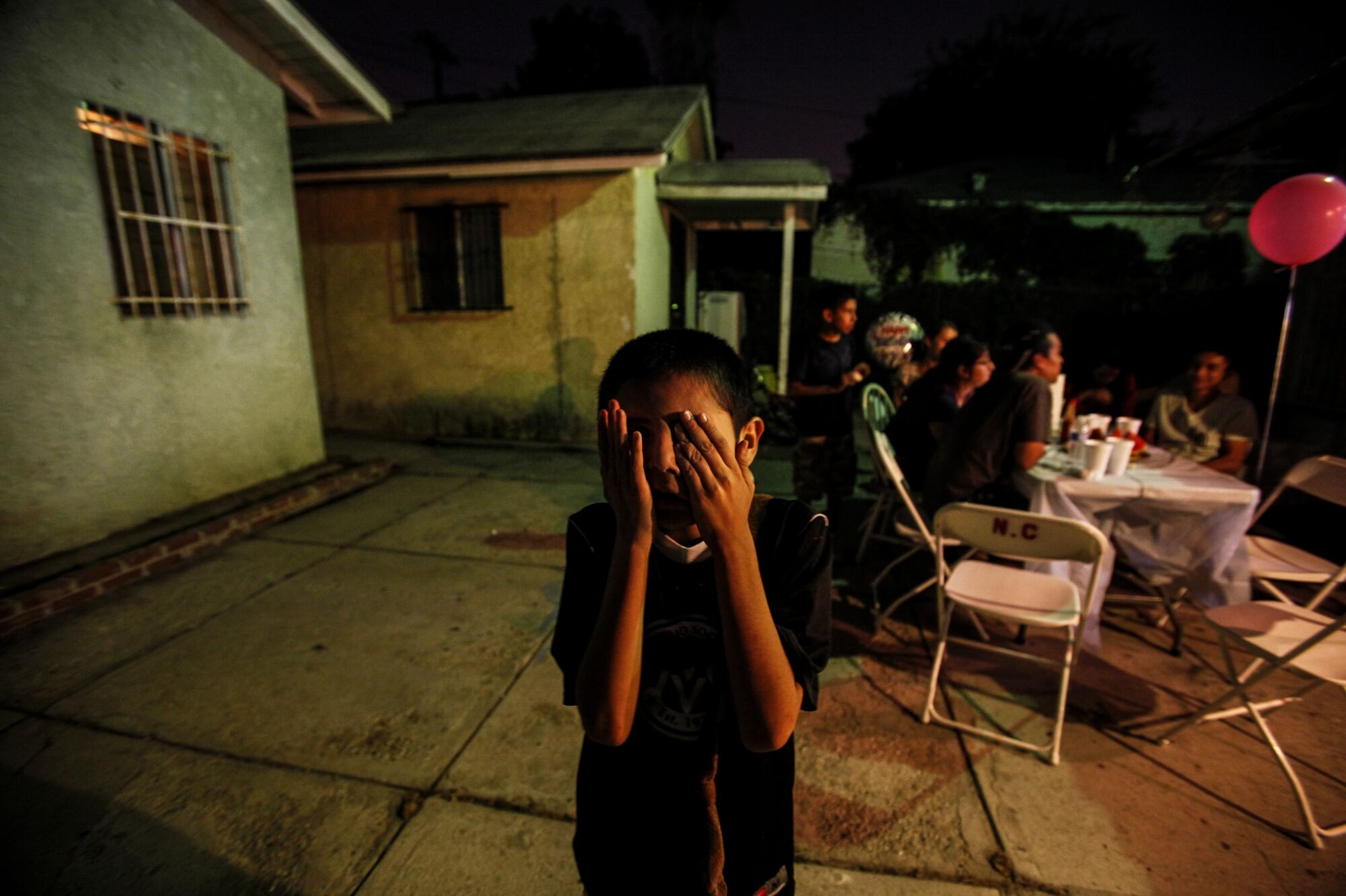Jese Castillo, 11, covers his eyes as he plays during his 11th birthday party in his back yard, in South Los Angeles.
