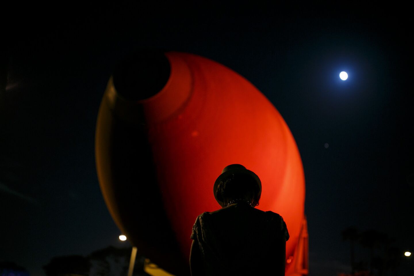 A woman takes a picture of the last shuttle fuel tank, ET-94, alongside an almost-full moon.