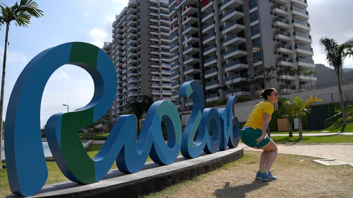 An Australian athlete poses for a photo in what is becoming a less populated Olympic village.