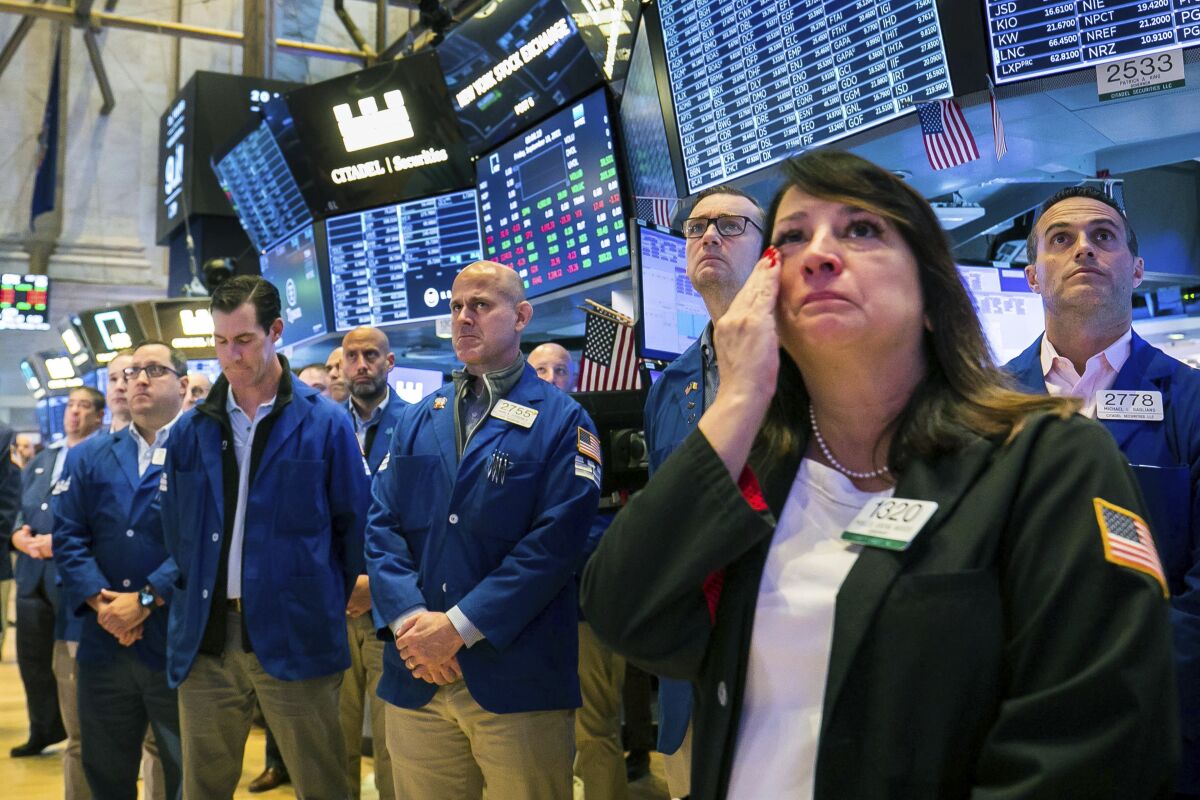 In this photo provided by the New York Stock Exchange, floor traders, including Phyllis Arena Woods, right, gather in remembrance on the eve of September 11th, on the Exchange trading floor, Friday Sept. 10, 2021. (Courtney Crow/New York Stock Exchange via AP)